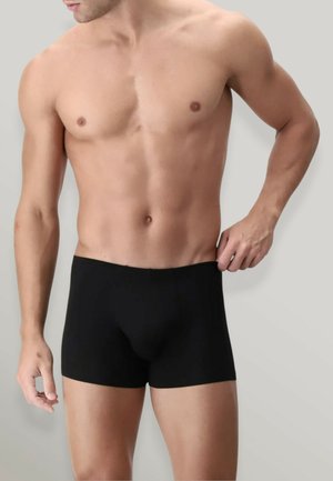 Boxer da uomo neri realizzati in tessuto morbido con cintura elastica, design aderente e senza cuciture visibili, abbinati a un torso nudo.