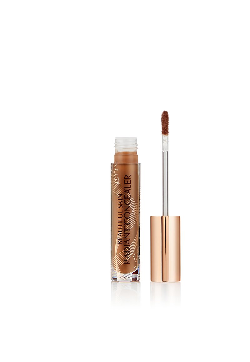 Tube of medium brown radiant concealer with wand applicator and rose gold cap on white background.