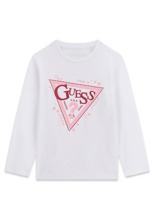 Chemise blanche à manches longues avec un logo triangulaire rose Guess et des cœurs décoratifs ainsi qu'un texte au centre.