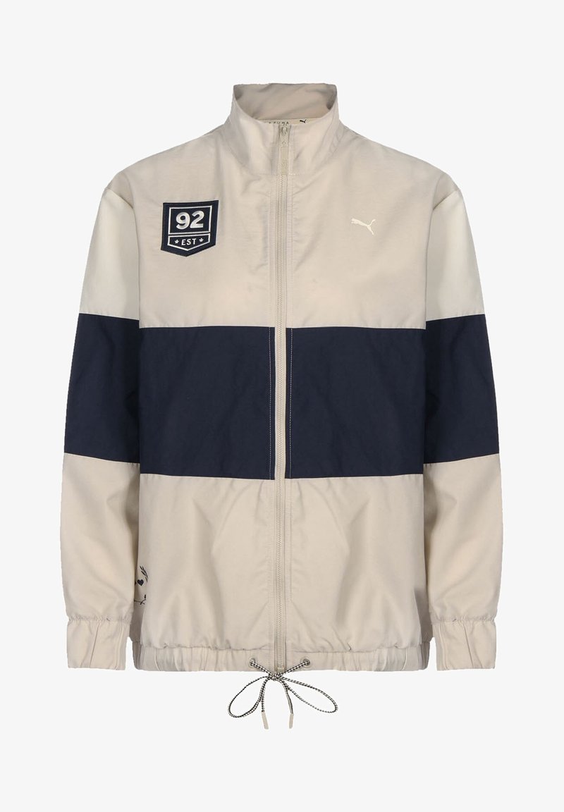 Veste beige et bleu marine avec fermeture éclair intégrale à l'avant, poignets élastiques, cordon de serrage à l'ourlet, et patchs affichant "92 EST" et un logo Puma.