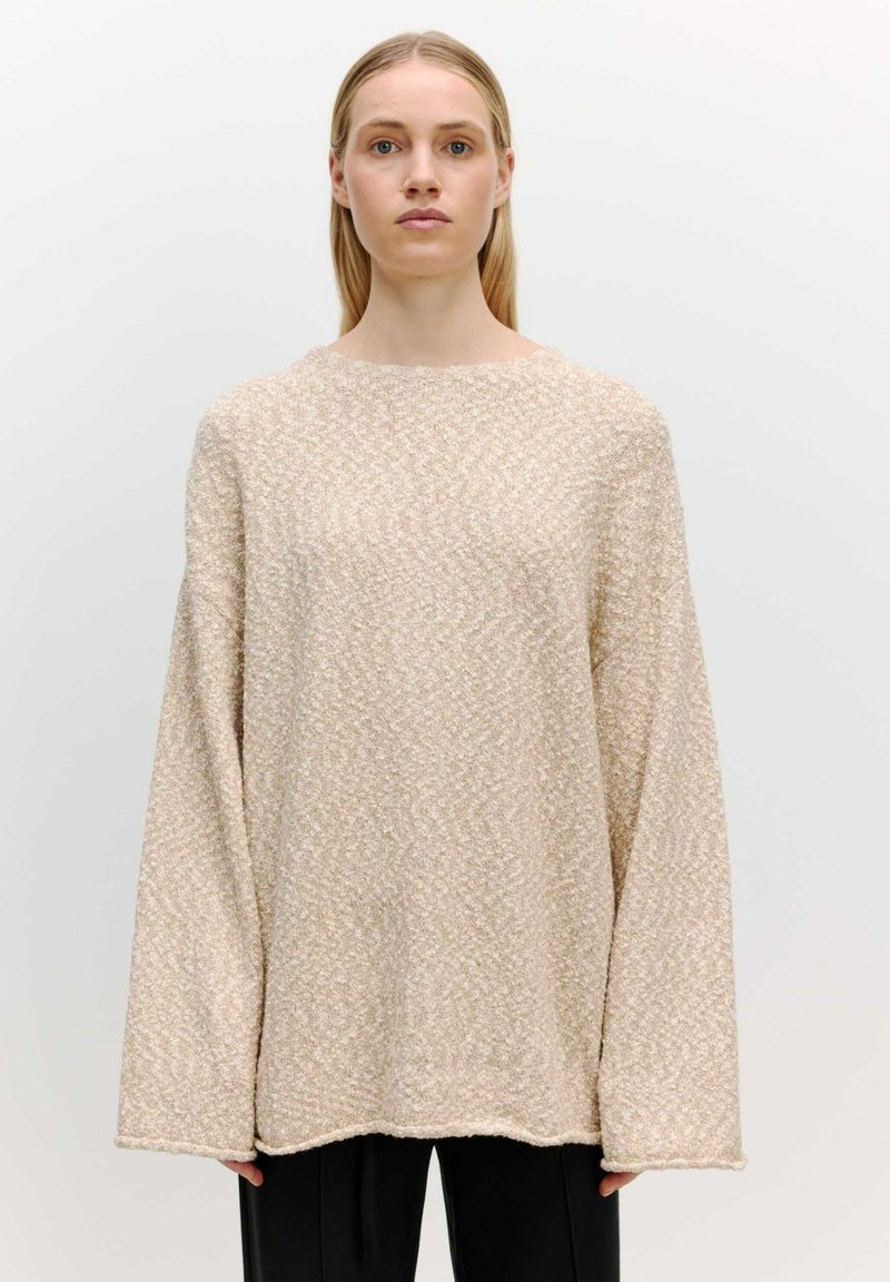Beige strukturierter Oversized-Pullover mit langen Ärmeln, Rundhalsausschnitt und lockerer Passform, der ein dezentes Muster und einen raw hem Detail aufweist.