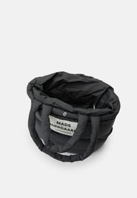 Cesta de armazenamento têxtil em preto, em material acolchoado. Apresenta pegas acolchoadas e um rótulo com o logótipo "MADS NØRGAARD COPENHAGEN". Forma redonda.