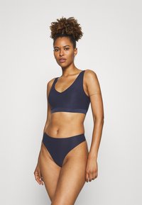 Marineblauwe bralette en hooggesneden bikini set gemaakt van gladde stof, met een v-hals ontwerp en brede banden voor comfort.