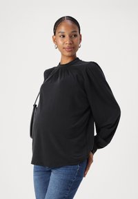 Black long-sleeve blouse with puffed shoulders and a rounded neckline, paired with blue jeans; smooth fabric with no visible patterns.