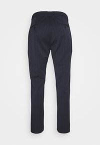 Pantalon bleu marine à rayures fines en tissu à la texture lisse. Il présente une coupe ajustée avec deux poches arrière et une jambe fuselée.