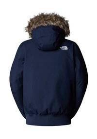 Granatowa, ocieplana kurtka z kapturem wyłożonym futrem, ściągaczami na rękawach oraz logo North Face na górnej części pleców. Gładki materiał zewnętrzny.