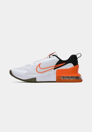 Zapatilla deportiva blanca con parte superior de malla texturizada, acentos en negro y naranja, suela de goma gruesa y una sección de cojín de aire transparente en el talón.