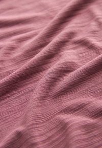 Textília z mäkkého, textúrovaného materiálu; svetloružová farba s jemnými horizontálnymi pruhmi a hladkým padaním, naznačujúcim ľahký materiál.
