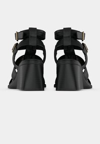 Μαύρα πλατφόρμες σανδάλια με πολλαπλές λουράκια, ρυθμιζόμενες αγκράφες και λείο υφασμένο επάνω μέρος. Διαθέτουν σταθερό, καμπυλωτό τακούνι.