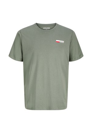 Dreng stående iført grøn kortærmet skjorte, beige cargoshorts, hvide sokker og hvide sneakers mod ensfarvet baggrund.