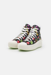 Czarne sneakersy typu high-top z tkaniny, ozdobione kolorowym wzorem owoców i kwiatów, białymi sznurówkami oraz masywną białą podeszwą z zielonym akcentem.