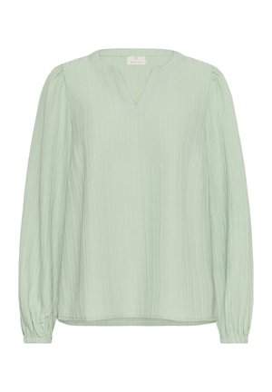 Hele roheline pluus V-kaelusega, pikkade varrukatega ja kogutud mansettidega. Tekstuuriga kangas on varustatud vertikaalsete triipudega ja lõige on mugav.