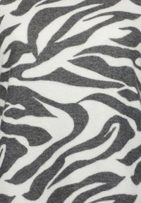 Kangas, jossa on zebrakuosiset mustat ja harmaan epäsäännölliset raidat valkoisella taustalla; pehmeä, teksturoitu materiaali, jossa on sileä pinta.