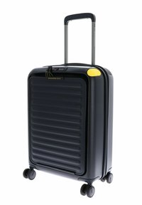 Valise rigide noire avec des rainures horizontales, poignée rétractable, accent jaune et quatre roues pour la mobilité. Comprend un cadenas à combinaison.