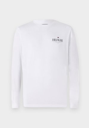 Bílý dlouhý rukáv tričko vyrobené z bavlny. Obsahuje malé černé logo "HILFIGER" s červenými a modrými akcenty v oblasti hrudi.