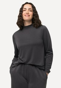 Dunkelgraues Langarmshirt mit hohem Kragen, aus weichem Stoff gefertigt. Es hat eine lockere Passform und dezente Drapierungen an der Taille.