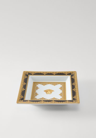 Kvadrātveida porcelāna šķīvis ar melnu un zelta apmali, izšūts ar sarežģītām ziedu motīvu rakstiem un centrālo medaļonu ar sejas attēlu.