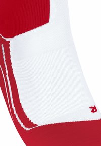 Rote und weiße Sportsocke mit enger Passform, ausgestattet mit einer strukturierten Oberfläche und einem wellenförmigen roten Muster am Knöchel, mit Markenbeschriftung.