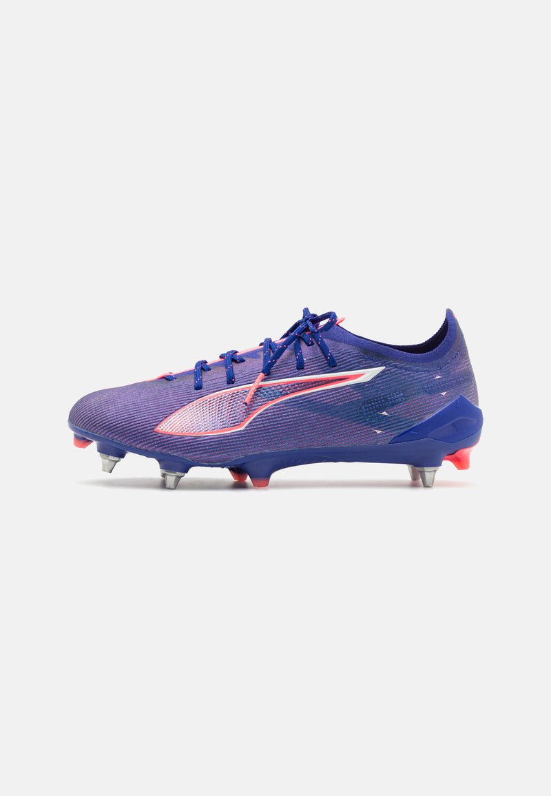Scarpa da calcio viola con un design testurizzato, caratterizzata da dettagli rosa, un logo bianco e tacchetti metallici per la trazione su superfici erbose.