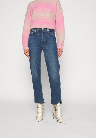 Maglione lavorato a maglia in ombre rosa chiaro e crema, jeans a vita alta blu con taglio dritto e stivaletti alla caviglia in stampa pitone argentata con punta affusolata.
