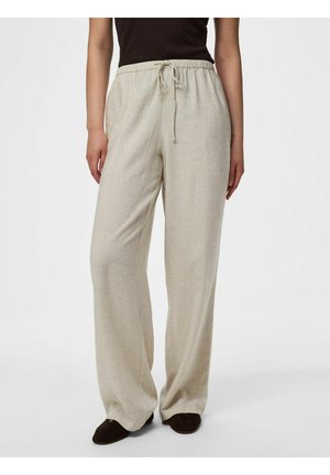 Personne portant un pantalon beige à jambes larges avec une taille élastique et un cordon, associé à un haut noir et des chaussures foncées.