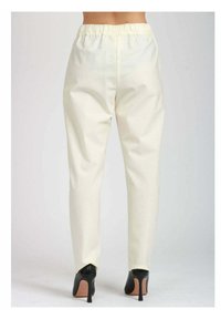 Pantaloni bianchi su misura con vita elastica, tessuto liscio e gambe affusolate, abbinati a scarpe con tacco nero.