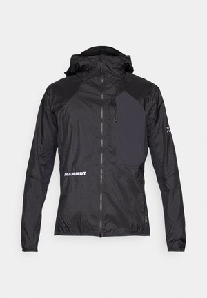Let jakke i sort med lynlås foran, hætte og kontrasterende mørkt panel. Har "MAMMUT" logoet og struktureret stof.