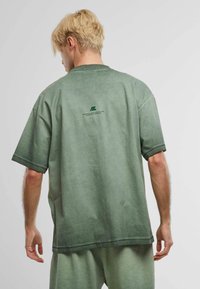 Zöld pamut oversized póló, kerek nyakkivágással, enyhe mintával a hátsó oldalon és laza fit. Puha tapintás, rövid ujjak.