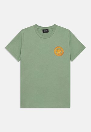Tricou verde din bumbac, cu mâneci scurte, decolteu rotund și un emblem galben rotund cu motiv de leu pe pieptul stâng.