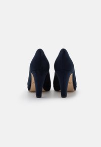 Navy blue high heels made of suede, featuring a closed toe and a sleek silhouette with a subtle curved design.