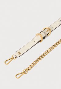 Δερμάτινος ιμάντας σε κρεμ χρώμα με χρυσά αξεσουάρ. Διαθέτει σχέδιο με αλυσίδα, μεταλλικά κλιπς και κυκλικούς κρίκους για προσαρμογή.