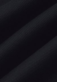Czarny teksturowany materiał o szorstkim splocie, wyeksponowany w fałdach i zmarszczkach. Skupia się na głębokim kolorze i gładkim wyglądzie powierzchni.