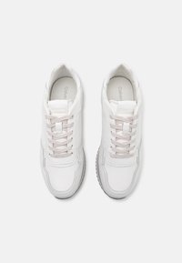 White sneakers with smooth leather upper, round toe, and tonal laces. Features subtle branding and a light gray rubber sole.