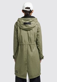 Jachetă khaki cu glugă, cordon la talie, manșoane cu nasturi și patch cu logo. Textură netedă și design de lungime medie. Îmbrăcăminte practică pentru activități în aer liber.