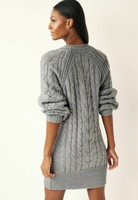 Abito maglione grigio oversize lavorato a maglia con motivo a trecce, polsini e orlo a costine. Caratterizzato da un collo tondo e maniche voluminose.