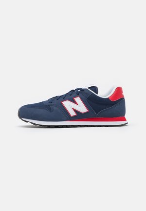 Zapatilla deportiva para hombre en azul marino y rojo con logotipo "N" blanco y forro interior acolchado blanco sobre un fondo liso.
