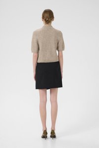 Beige knit short-sleeve top, black mini skirt, and olive green heeled shoes, viewed from the back against a plain background.