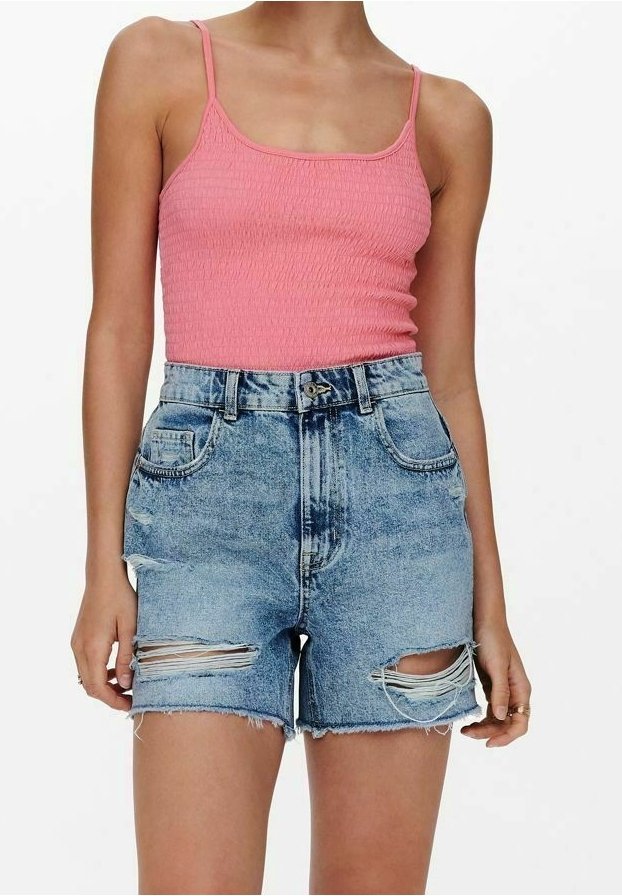 Femme portant un haut sans manches rose et un short en jean bleu clair taille haute avec des détails déchirés aux cuisses.
