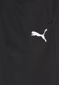 Zwarte sportbroeken met een gladde textuur en een wit springend kattenlogo aan de linkerkant. Heeft een slim fit en een elastische tailleband.