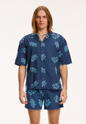 Navy short-sleeve shirt and shorts set featuring turquoise abstract plant patterns. Made from smooth fabric with a button front closure.