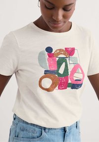 T-shirt bianco in cotone con forme e linee astratte multicolori in stampa sui toni del rosa, verde, blu e marrone sul davanti. Maniche corte.