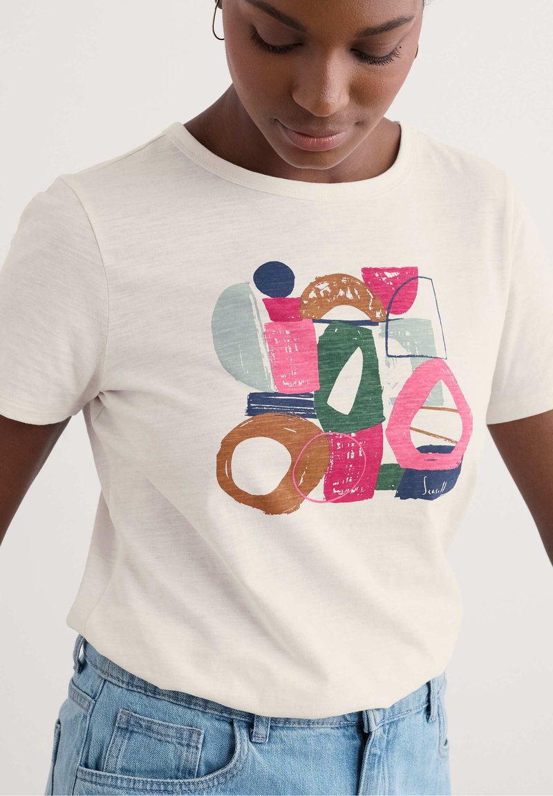 T-shirt bianco in cotone con forme e linee astratte multicolori in stampa sui toni del rosa, verde, blu e marrone sul davanti. Maniche corte.
