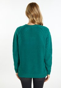 Maglione lavorato a maglia color teal con motivi a treccia testurizzati, scollatura rotonda e maniche lunghe. Presenta polsini e orlo a coste per un tocco di dettaglio in più.