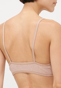 Light brown bralette with thin straps, made from textured fabric. Features a simple design with a comfortable, stretchy fit.
