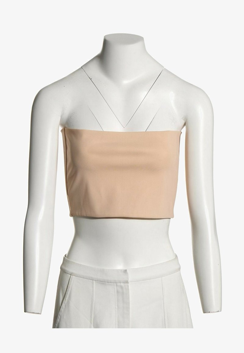 Mannequin portant un crop top beige sans bretelles et un pantalon blanc taille haute sur un fond uni.