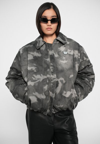 Grijze camouflage bomberjack met een rits aan de voorkant, grote kraag en subtiele logo-accenten. Gemaakt van een zachte, gestructureerde stof met een oversized pasvorm.