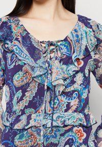 Fialové šaty s květinovým vzorem, které mají rýhovaný výstřih, požehnanou detaily a texturovaný korzet. V designu jsou živé modré, zelené a červené barvy.