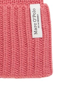 Bonnet rose tricoté avec un design côtelé et une étiquette tissée attachée, indiquant "Marc O'Polo". Texture douce avec un aspect confortable.
