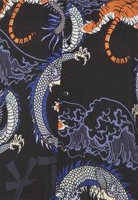 Skjorte med blå og hvid drage samt orange tiger mønstre på sort baggrund, med bølger og knaplukning ned i midten.