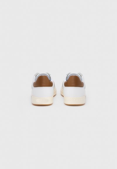 Λευκά αθλητικά παπούτσια με λείο δερμάτινο επάνω μέρος, καφέ λεπτομέρειες στη φτέρνα και κρέμ σόλες από καουτσούκ. Μινιμαλιστικός σχεδιασμός με δέσιμο με κορδόνια.
